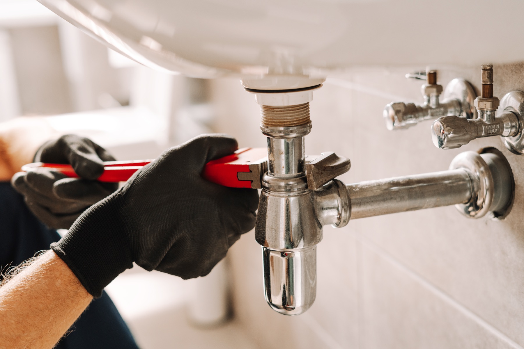 Plumber using a pipe wrench to repair a sink drain